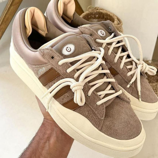 Pair of brown sneakers with white laces on a neutral background
