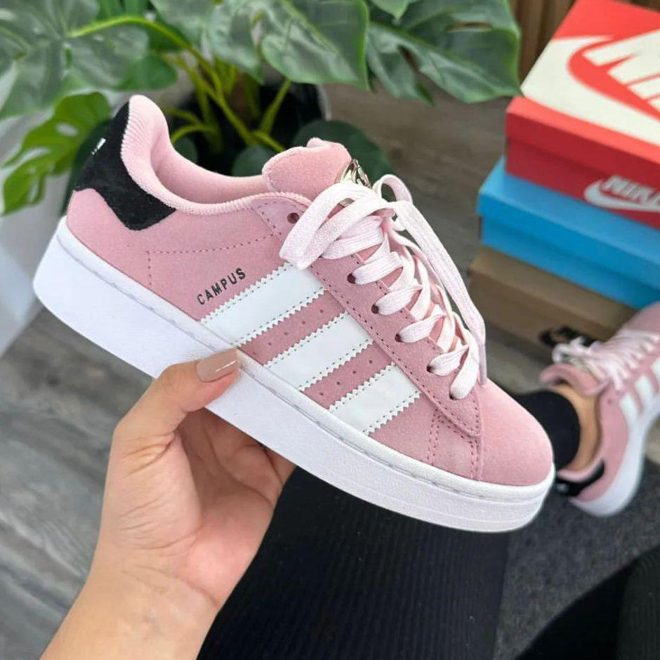 Pink Adidas sneaker held in a hand with blurred background