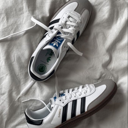 White sneakers with black stripes on a white fabric background