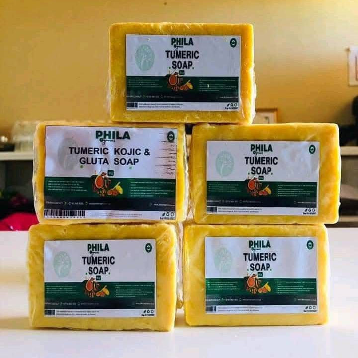Stack of yellow Phila Tumeric Soap bars on a white surface with a yellow wall in the background.