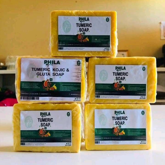 Stack of yellow Phila Tumeric Soap bars on a white surface with a yellow wall in the background.