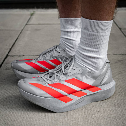 adizero Evo SL Gray sneakers with red stripes worn on a sidewalk