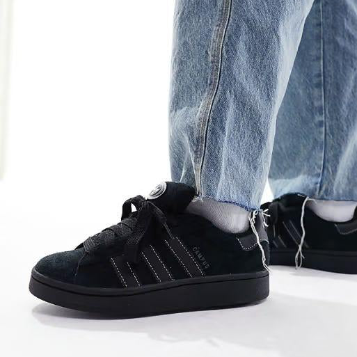 Black sneakers worn with light blue jeans on a white background