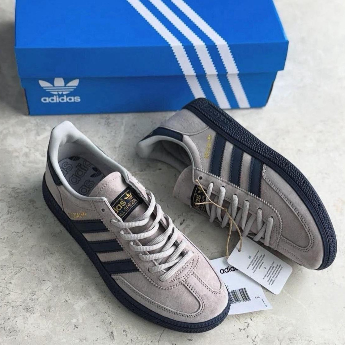 Pair of grey spezial Adidas sneakers with a blue box in the background