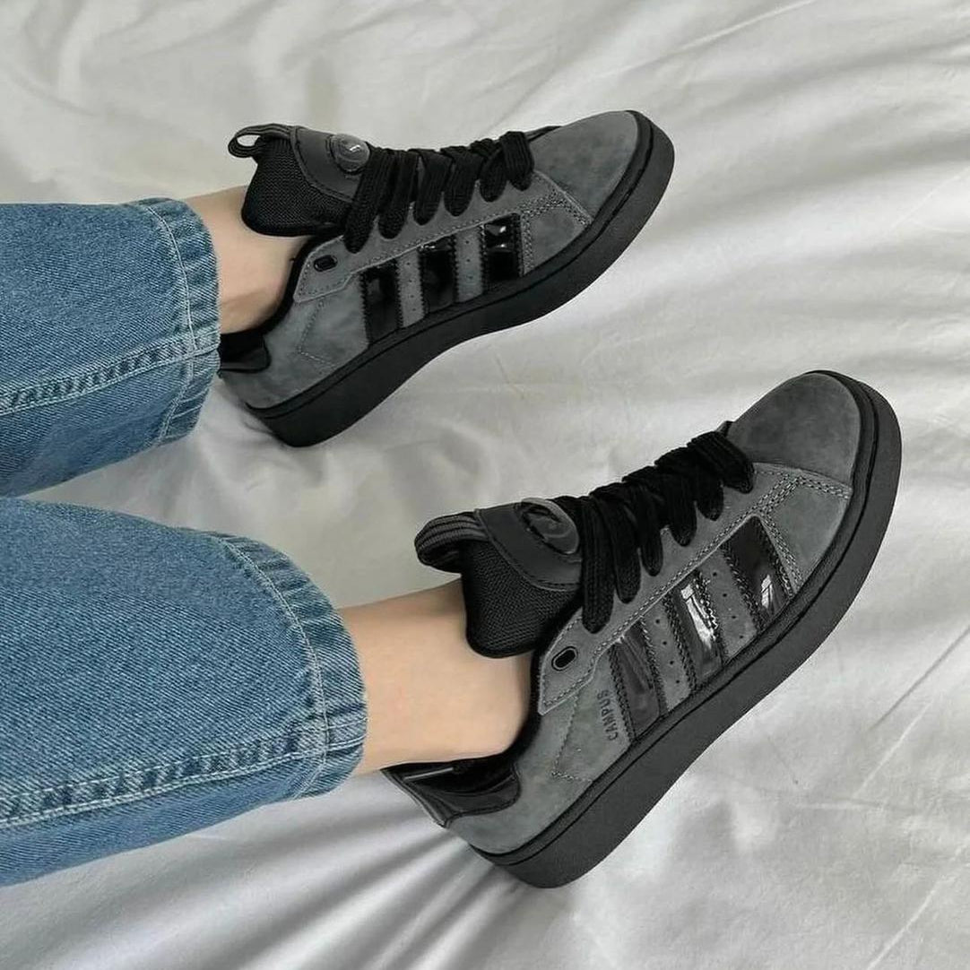 Gray sneakers with black stripes worn with blue jeans on a light gray background