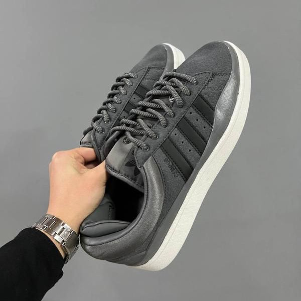 Person holding a pair of gray sneakers with white soles against a gray background