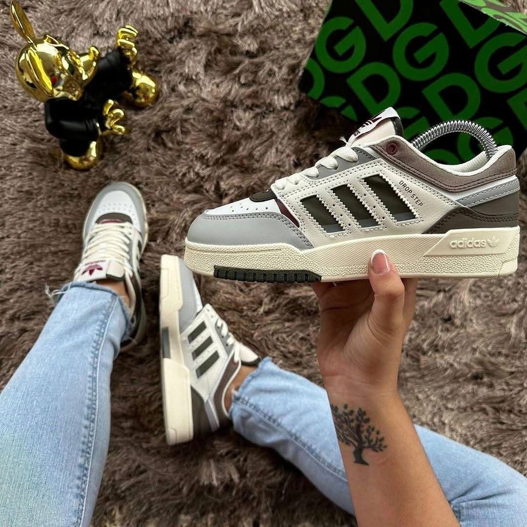 Person wearing Adidas sneakers on a textured surface with a green and black box in the background.