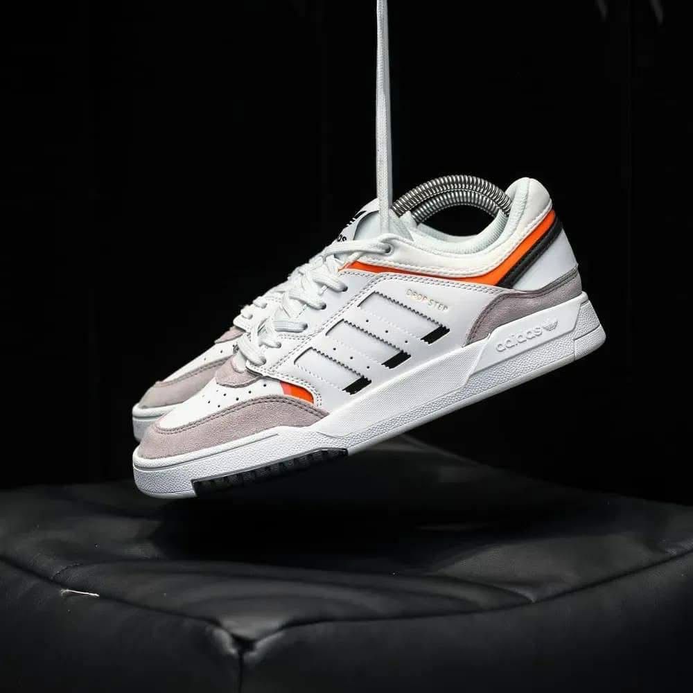 White and gray sneaker with orange accents on a black background