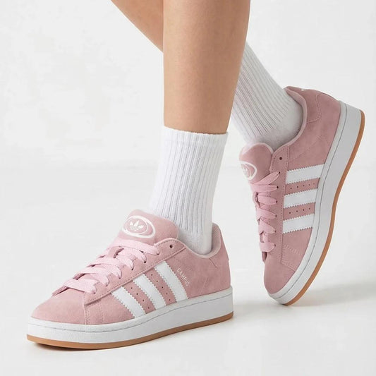 Pink Adidas campus sneakers with white stripes worn with white socks on a light background